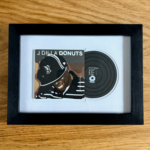 Framed J Dilla 'Donuts' vinyl record and cover on a wooden surface